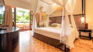 A bedroom with a four-poster bed, a bedside table, and a view of the outdoors.