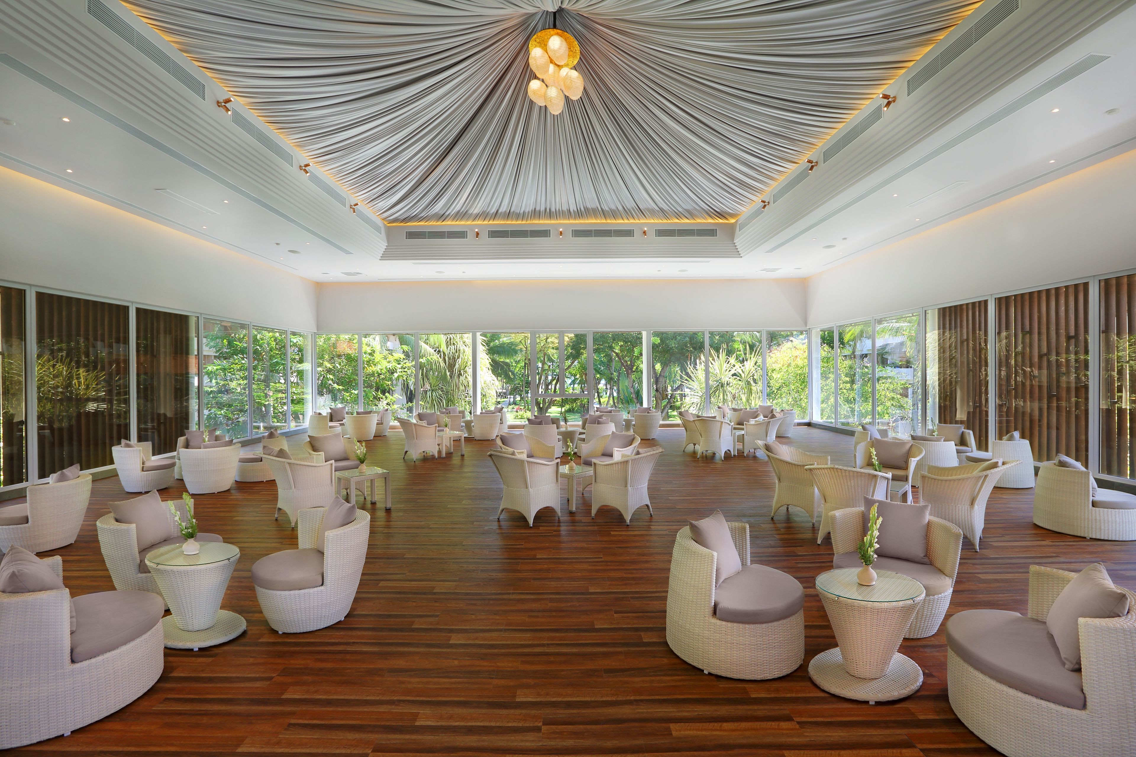 A spacious indoor area with multiple seating arrangements, large windows, and a unique ceiling design.