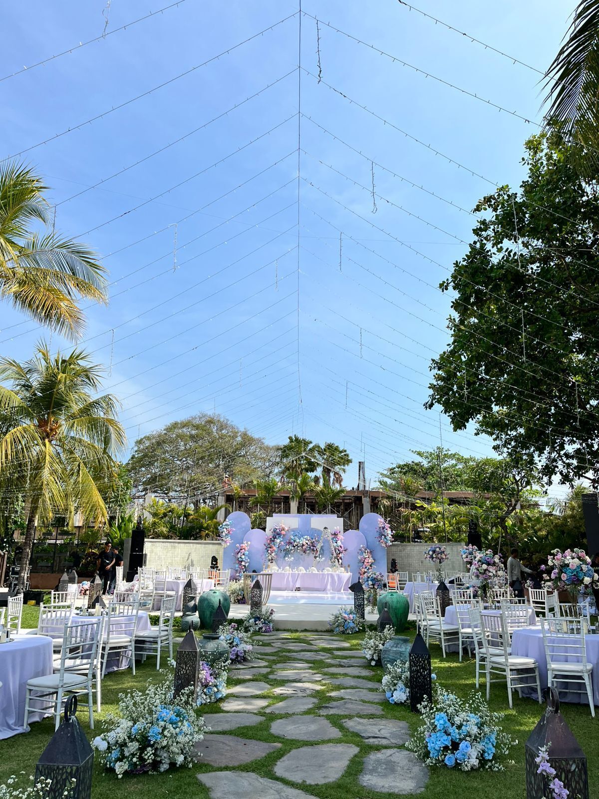Un lugar para bodas al aire libre con un escenario, decoraciones florales y asientos dispuestos en filas.