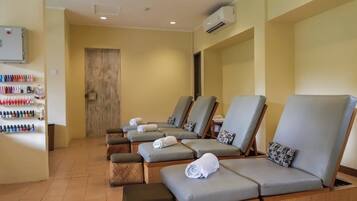 A room with multiple massage chairs, a wall-mounted air conditioner, and a shelf with various bottles.