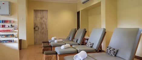 A room with multiple massage chairs, a wall-mounted air conditioner, and a shelf with various bottles.