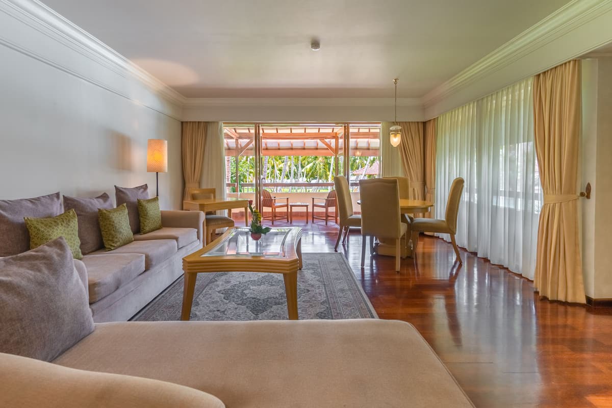 A spacious living room with a sofa, armchairs, a coffee table, and a dining area with chairs and a table.