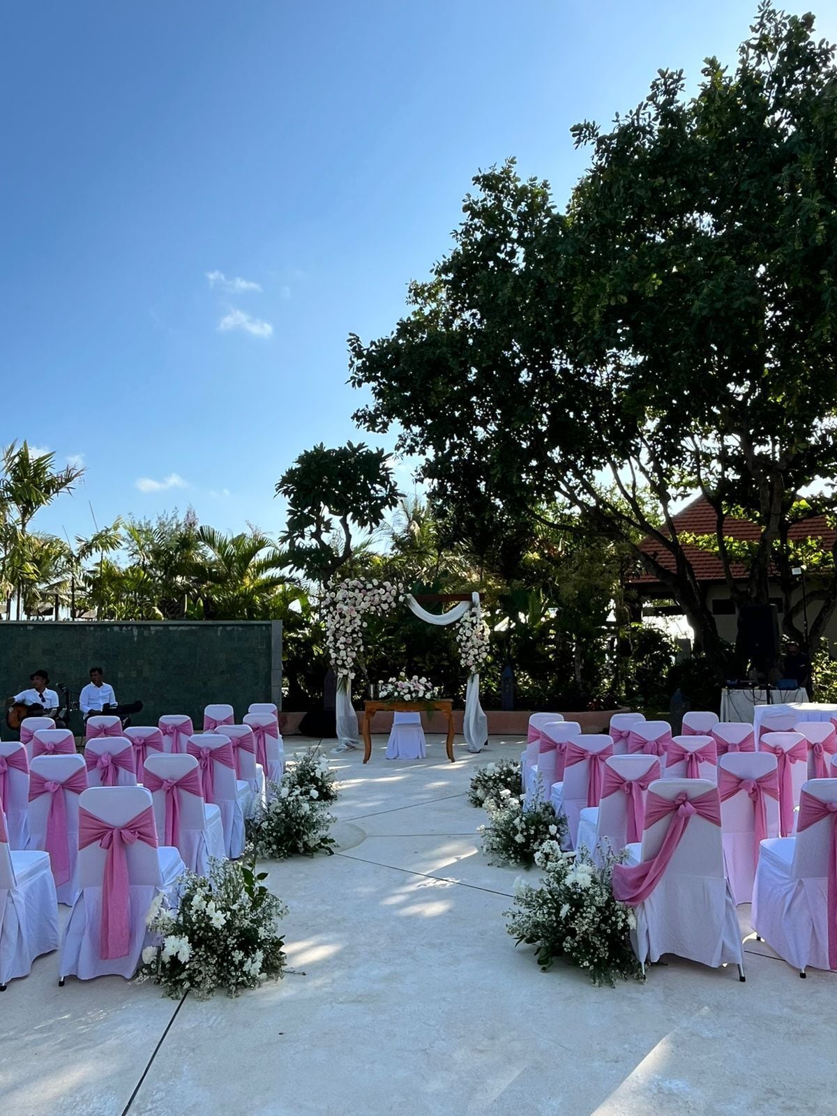 An outdoor wedding venue with rows of chairs and a floral arch.