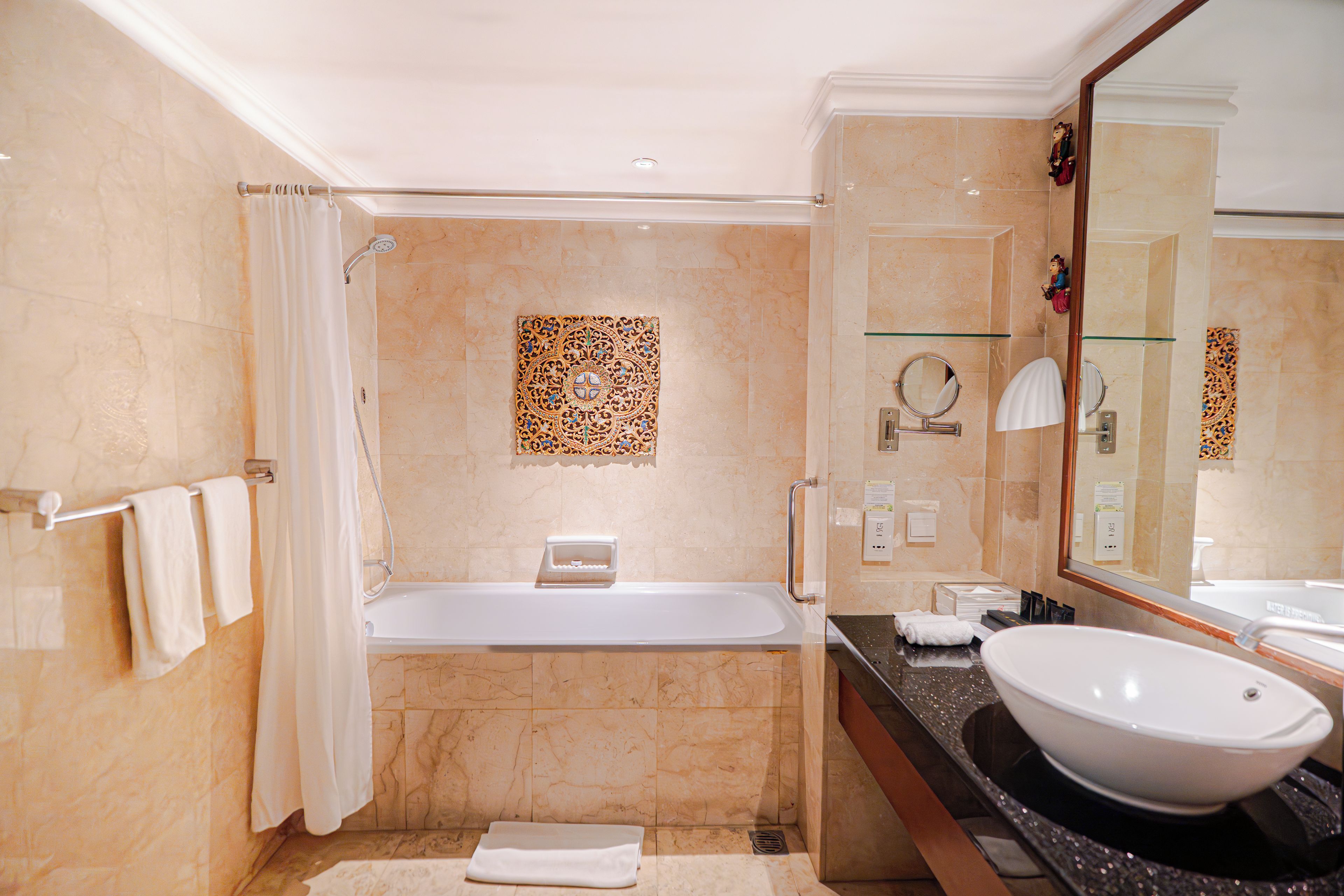 Une salle de bain moderne avec une baignoire, un grand miroir et un lavabo.