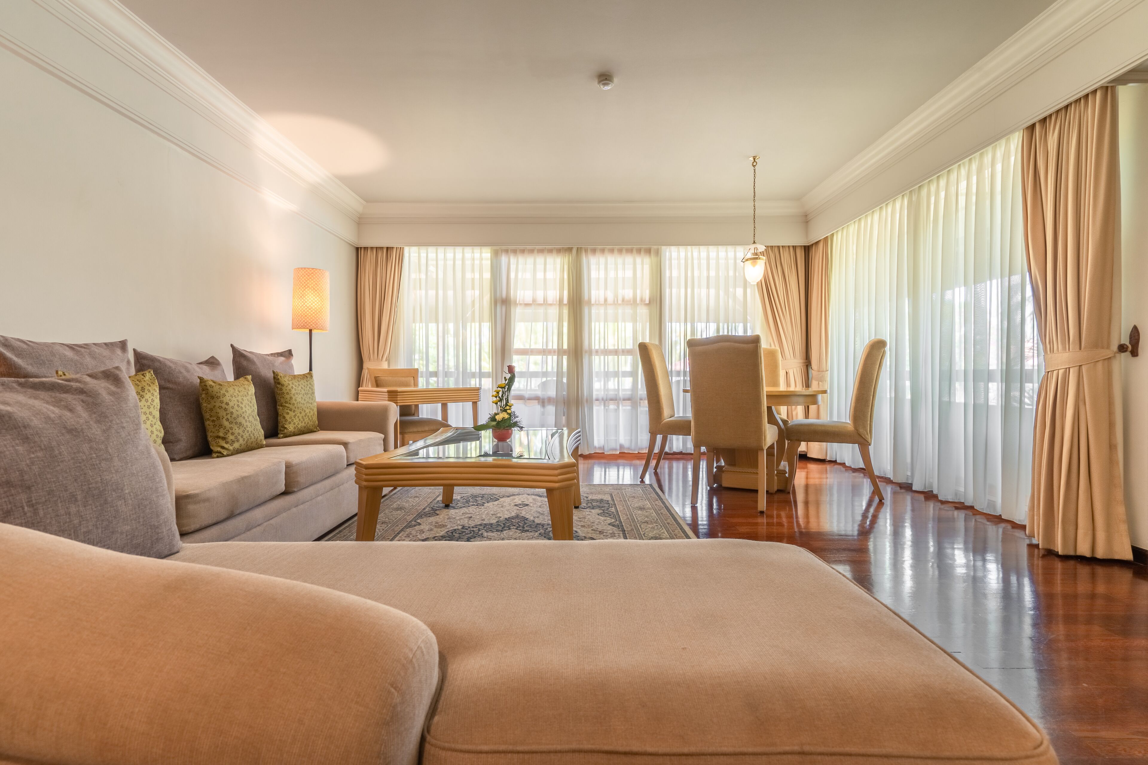 A spacious living room with a sofa, armchairs, a coffee table, and a dining area.