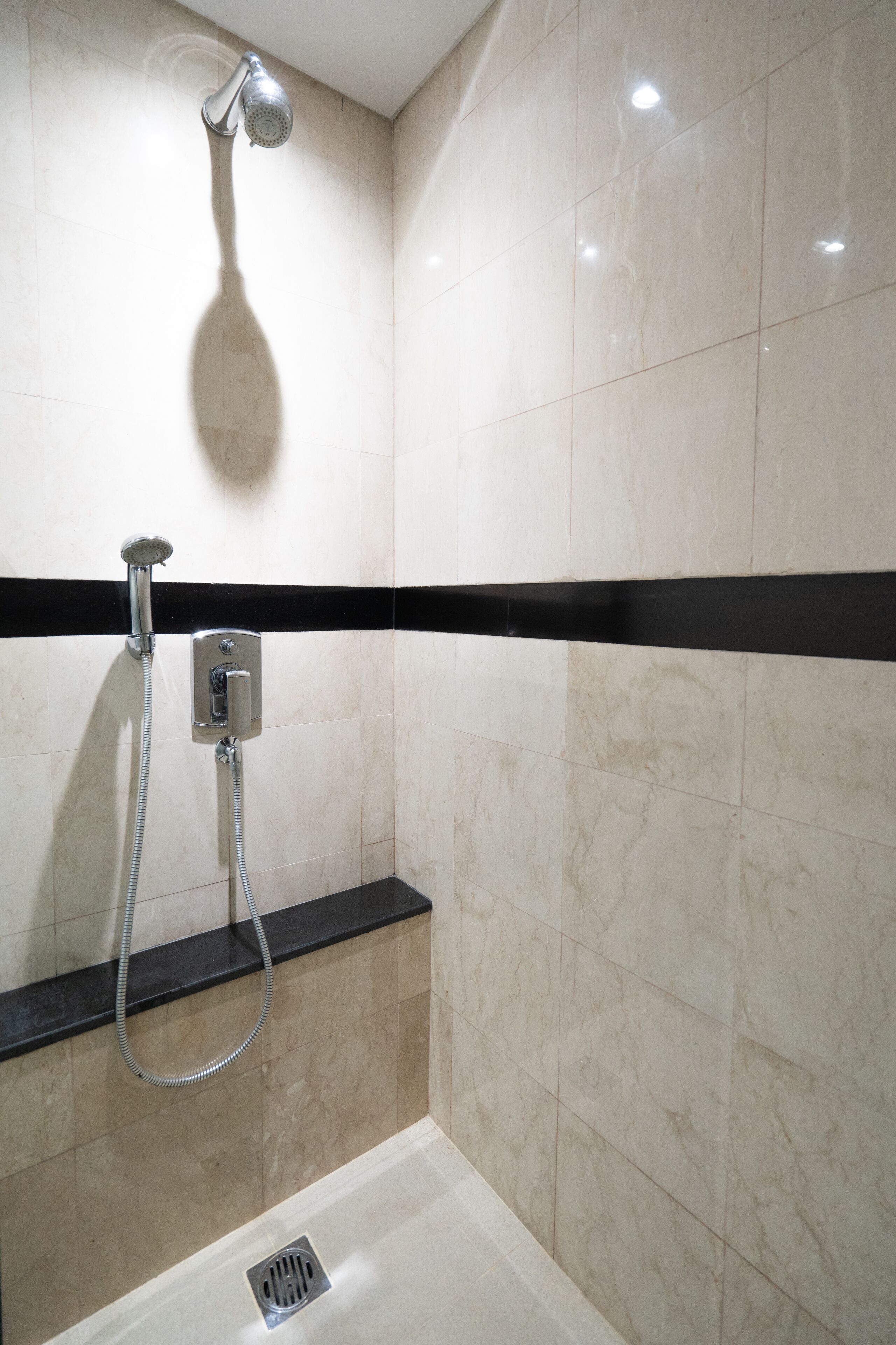 A modern bathroom with a shower, a black strip on the wall, and a drain.