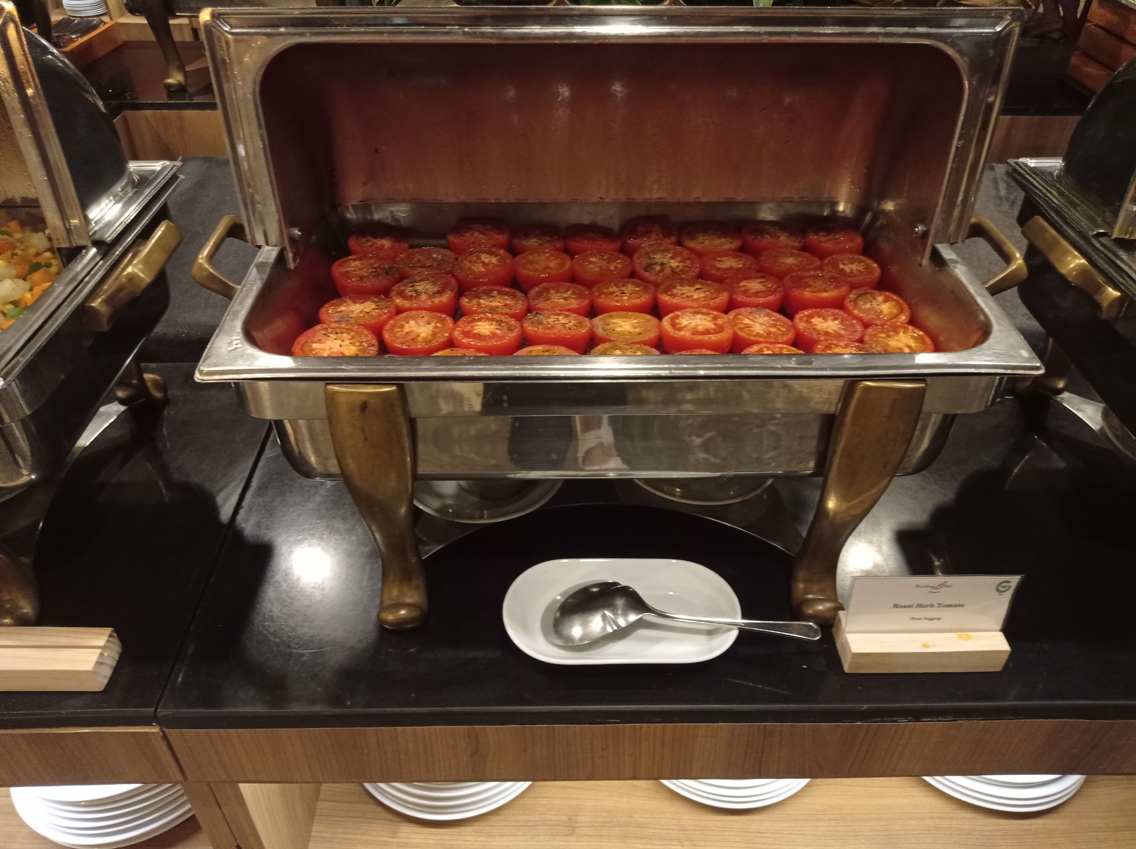 A buffet with a variety of food items, including a section with sliced tomatoes.