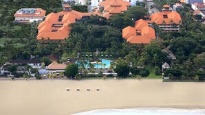 A coastal resort with multiple buildings, a swimming pool, and beach umbrellas.