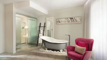 Features a bathtub, glass-enclosed shower, and contemporary chair.
