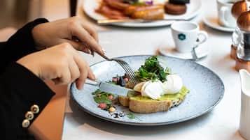 Una persona cortando un sándwich en un plato con un tenedor.