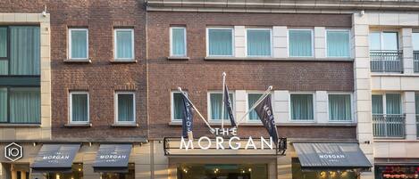 A hotel with a prominent sign reading "The Morgan Hotel." There are multiple windows on the facade, and the building has a modern architectural style.
