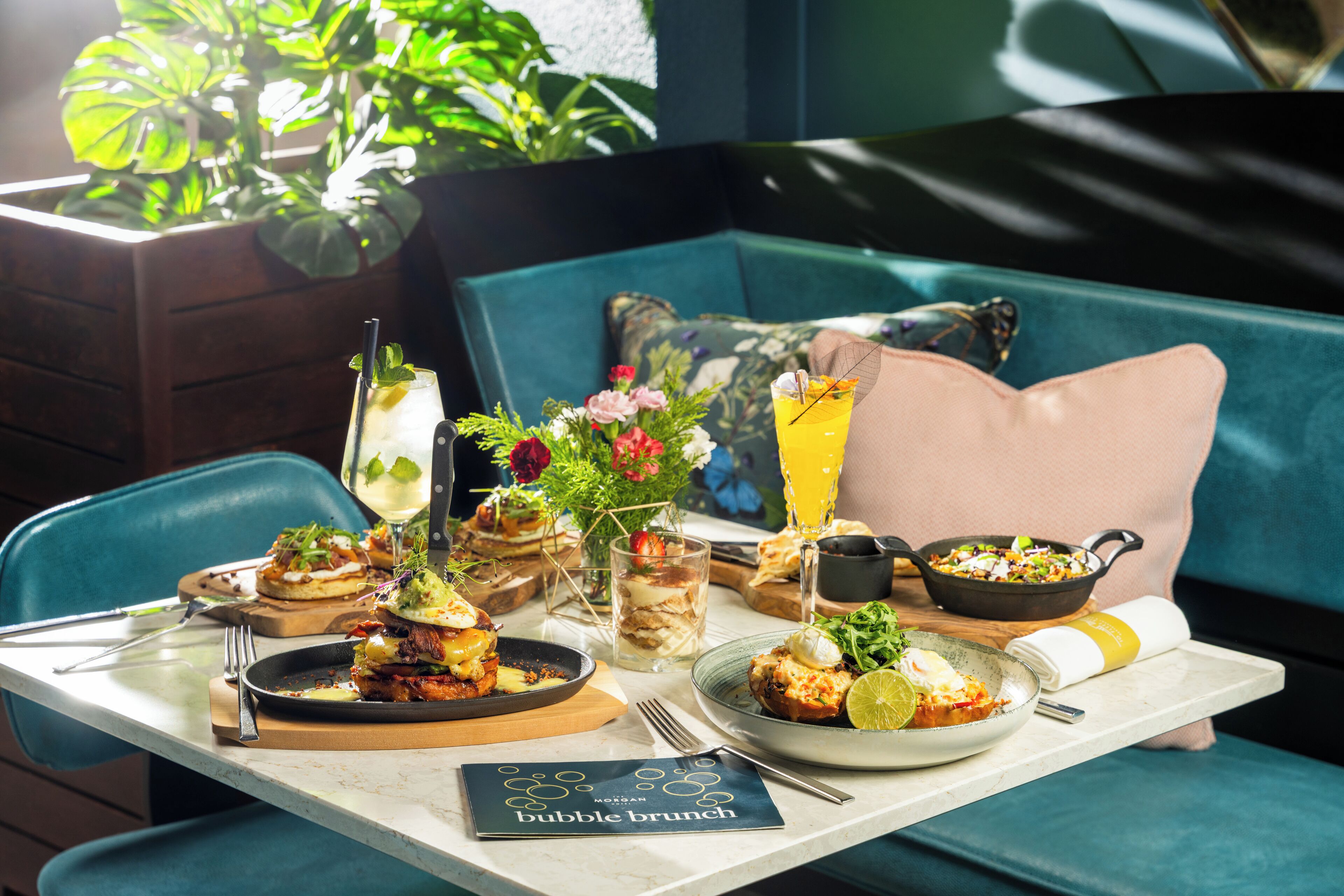 Una mesa de comedor con varios platos, bebidas y un menú que dice 'bubble brunch'.