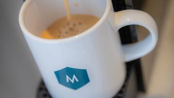 A coffee machine dispensing coffee into a white mug with a logo.