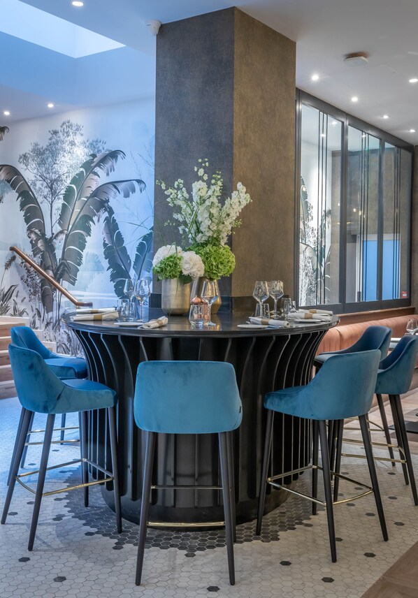 Un comedor moderno con una mesa redonda, sillas azules y una columna central.