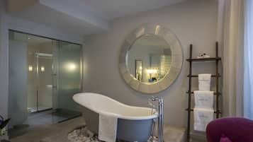 A modern bathroom with a freestanding bathtub, a large mirror, and a towel rack with branded towels.