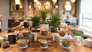 A buffet setup with various dishes and a sign listing salad options.