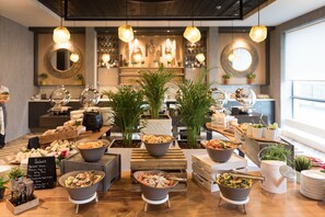 A buffet setup with various dishes and a sign listing salad options.
