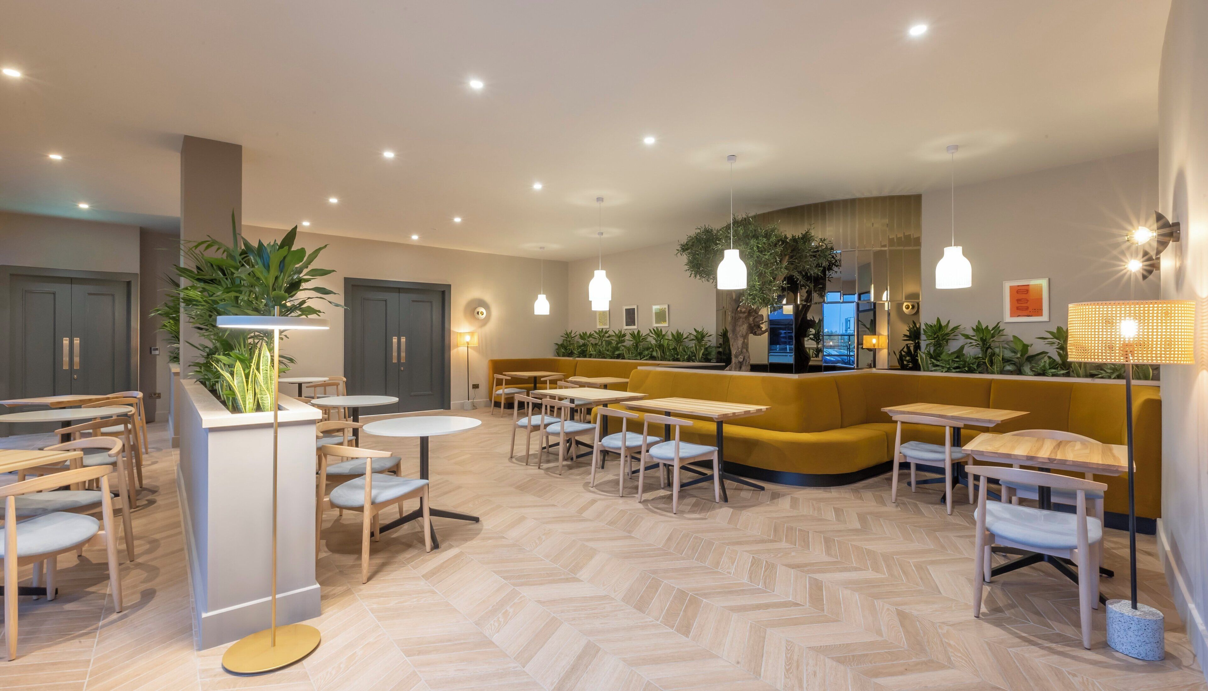 A modern interior with seating areas, tables, and plants.