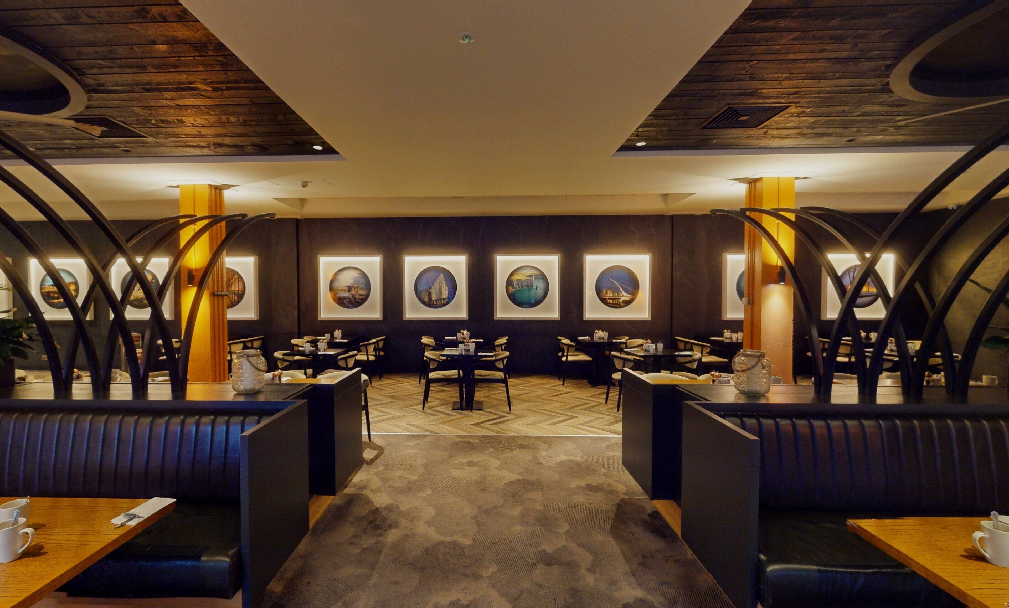 A restaurant with booths and tables, framed artwork on the walls, and a wooden ceiling.