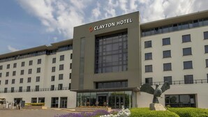 A Clayton Hotel building with a modern facade, large windows, and a statue of an eagle.