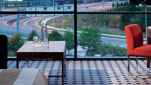 Habitación de hotel con un ventanal que ofrece vistas a un aeropuerto y un estadio.
