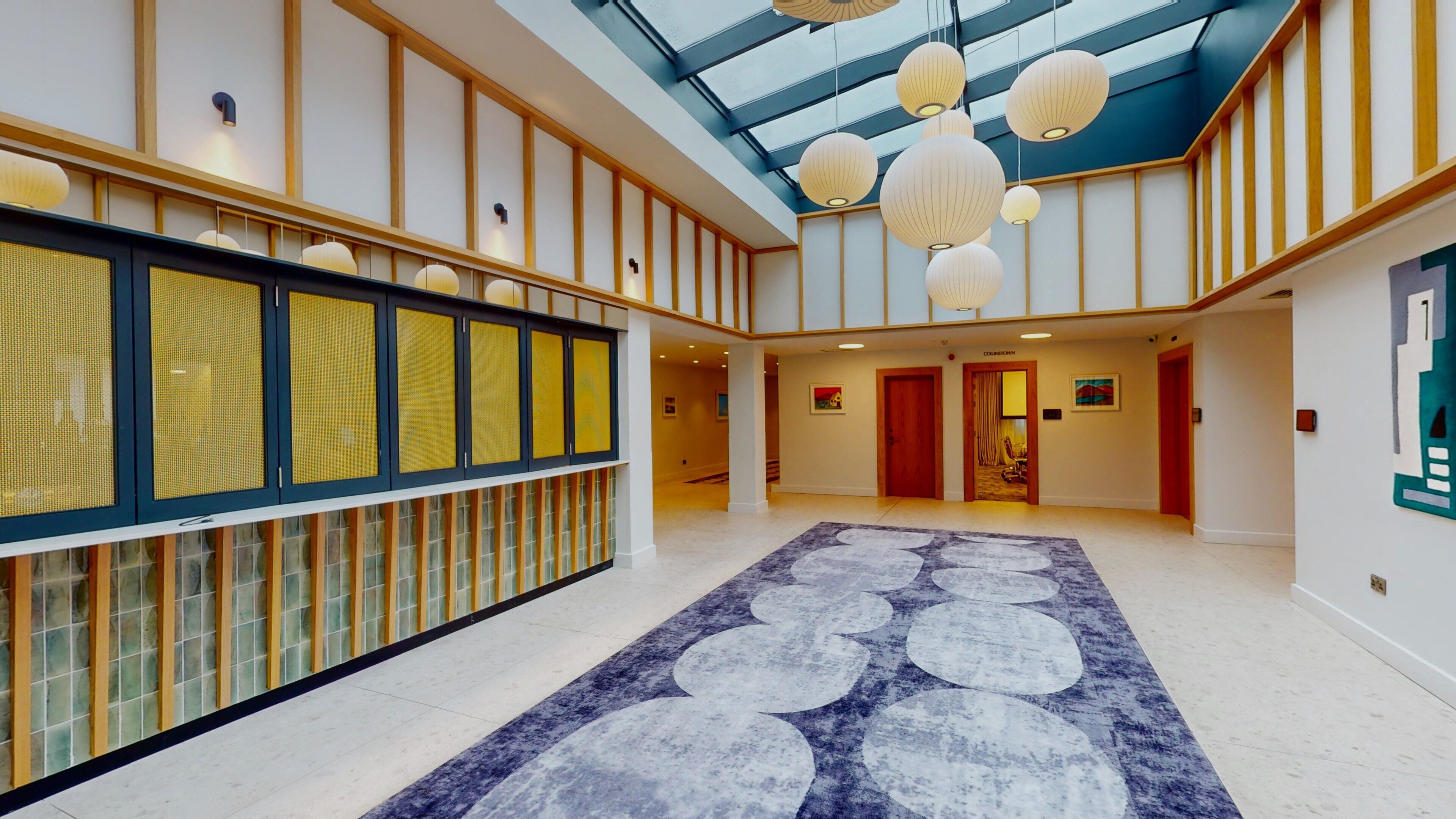 A spacious lobby with a high ceiling, a patterned carpet, and traditional lanterns.
