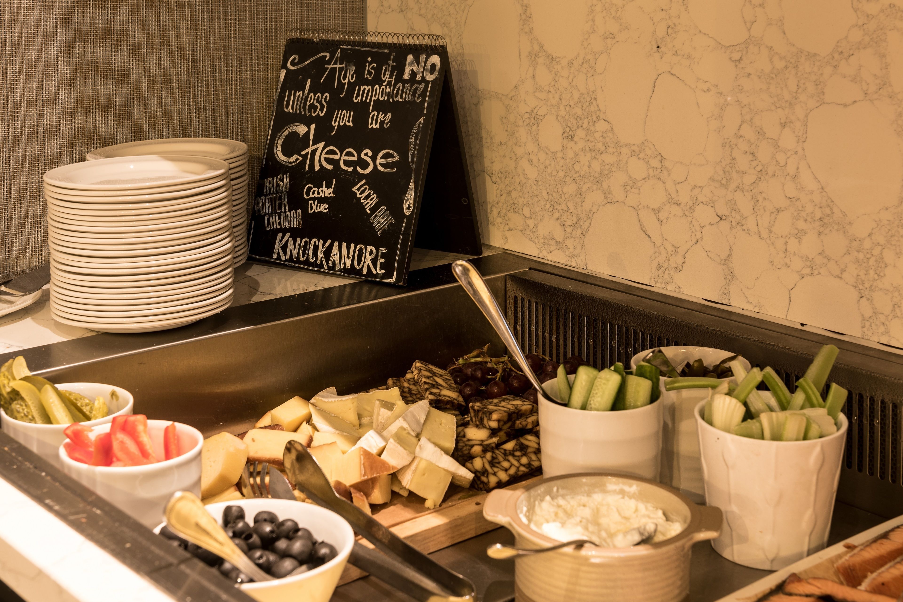 A buffet with various cheeses, fruits, and vegetables.