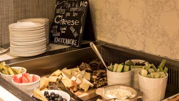 A buffet with various cheeses, fruits, and vegetables.