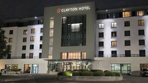 Un moderno edificio del Clayton Hotel con una entrada destacada, ventanas amplias y una fachada bien iluminada.