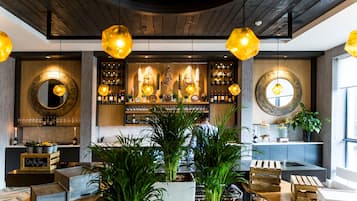 Un área de bar moderna con techo de madera, luces colgantes y un barman trabajando.