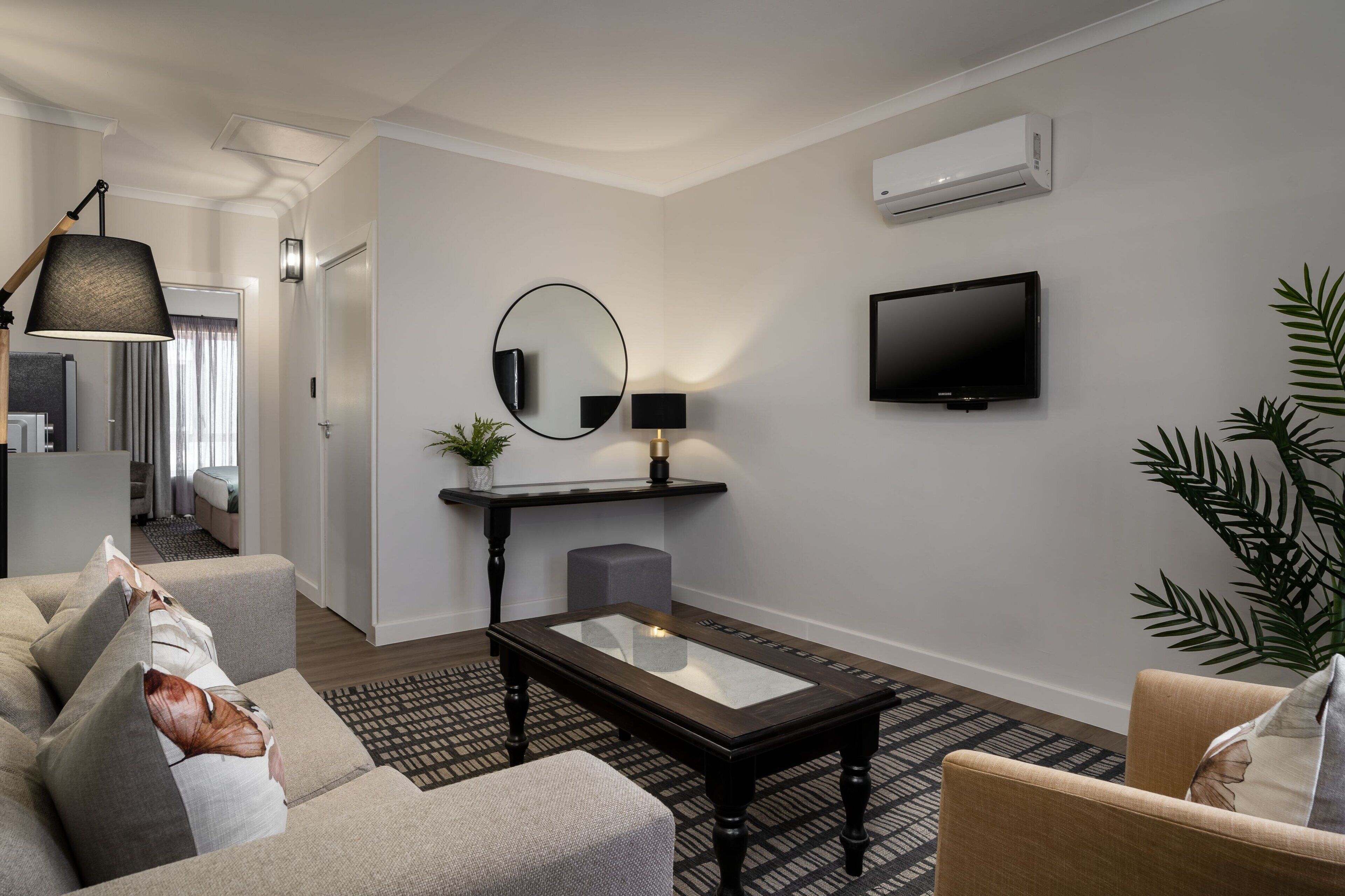 Una sala de estar moderna con sofá, una mesa de centro, televisor y espejo.