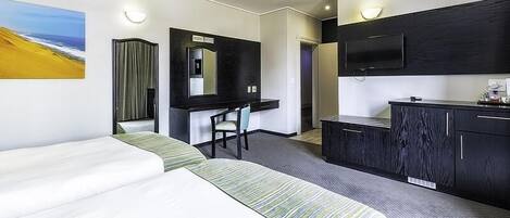 Una habitación de hotel con cama, escritorio, silla, televisor y minibar.