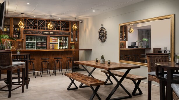 Una zona de bar con mobiliario de madera, un reloj en la pared y un espejo grande.