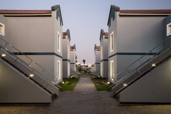 A corridor with two staircases leading to a central area with a pathway and small plants.