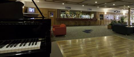 A piano, a bar area, and a seating area with a wooden floor and a carpeted section.