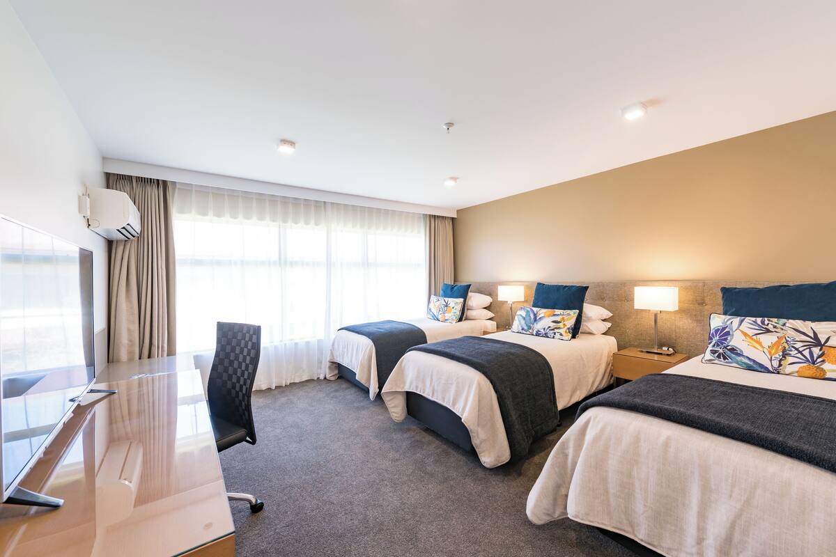 Une chambre d’hôtel avec deux lits, un bureau et une chaise.