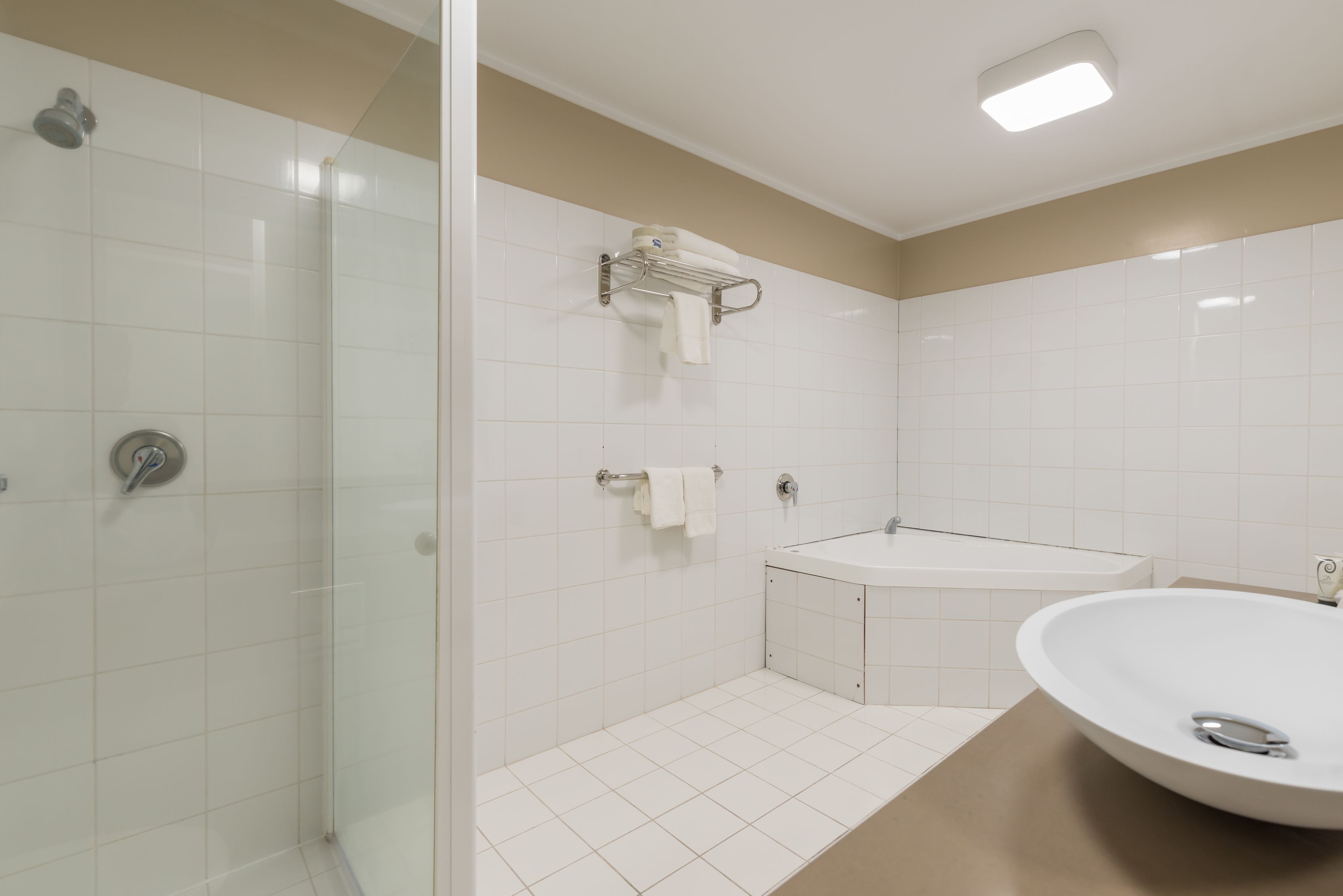 A modern bathroom with a glass shower enclosure, a freestanding bathtub, and a large oval sink.