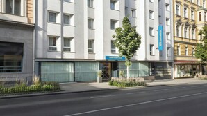 Een modern hotel met een witte gevel, meerdere verdiepingen en een plat dak.