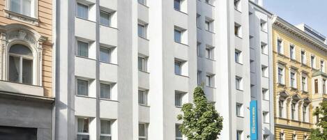 Un hotel moderno con fachada blanca, varios pisos y techo plano.