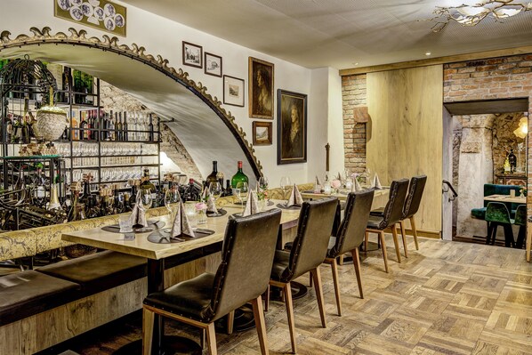 A bar area with a curved ceiling, wine bottles, glasses, and a dining setup with chairs and tables.