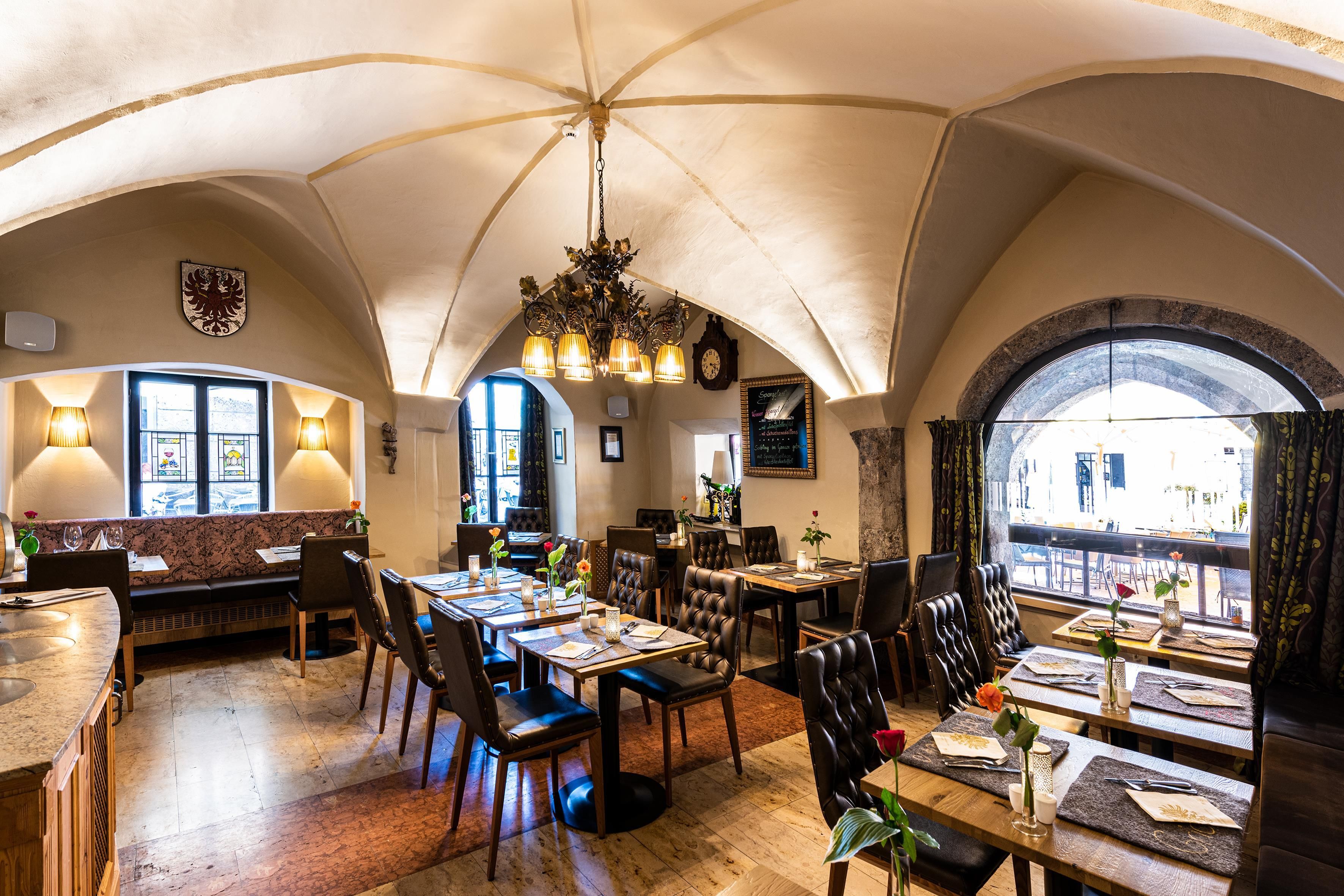 Interior de restaurant amb alts sostres apuntats, diverses taules i caires.