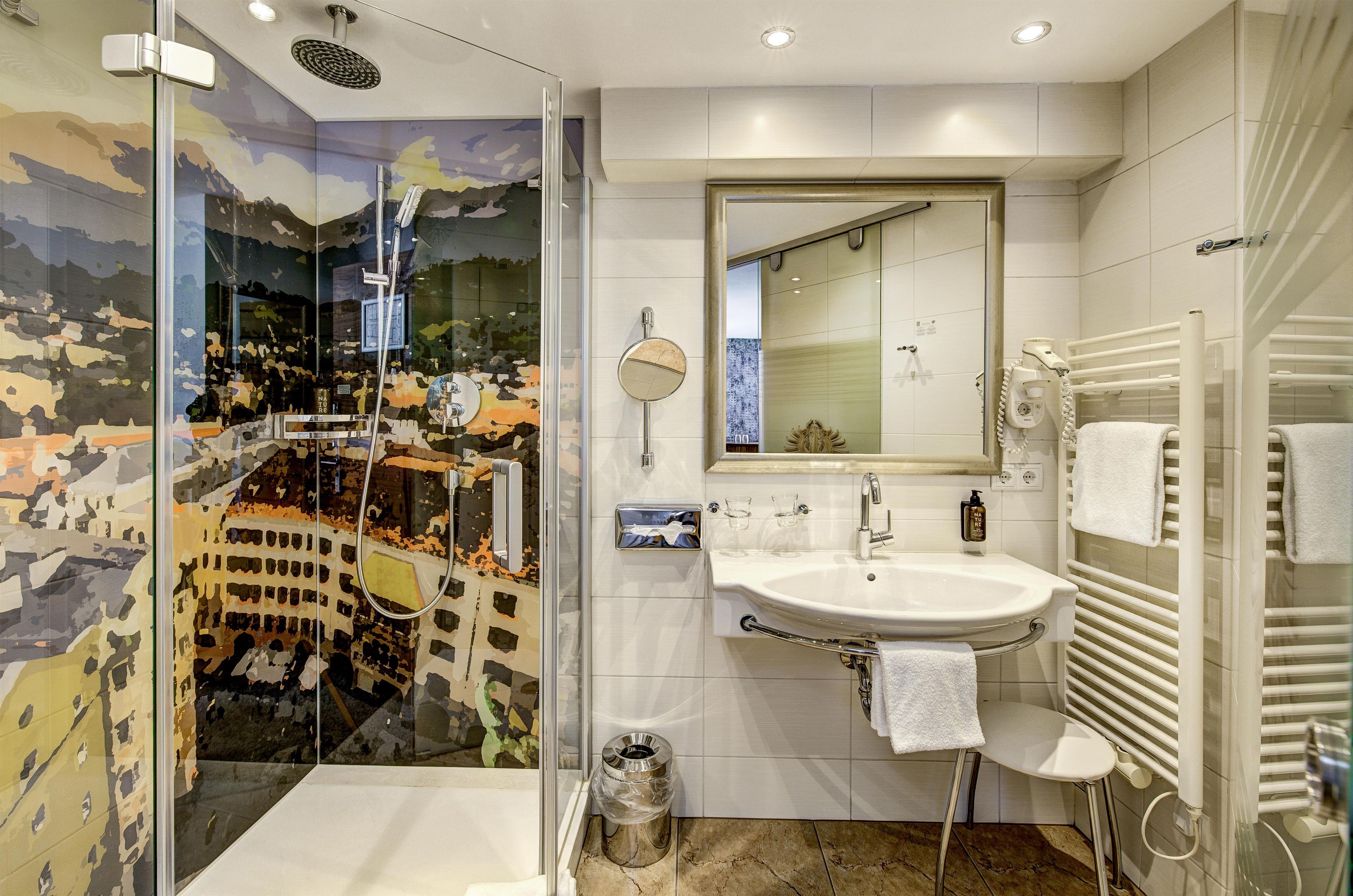 Un bagno con box doccia in vetro, un lavandino, uno specchio e un portasciugamani.