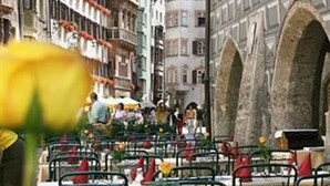 A street with outdoor seating, historic buildings, and a hanging lamp.