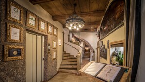 A grand staircase leading to a second floor, surrounded by framed certificates and a menu stand.