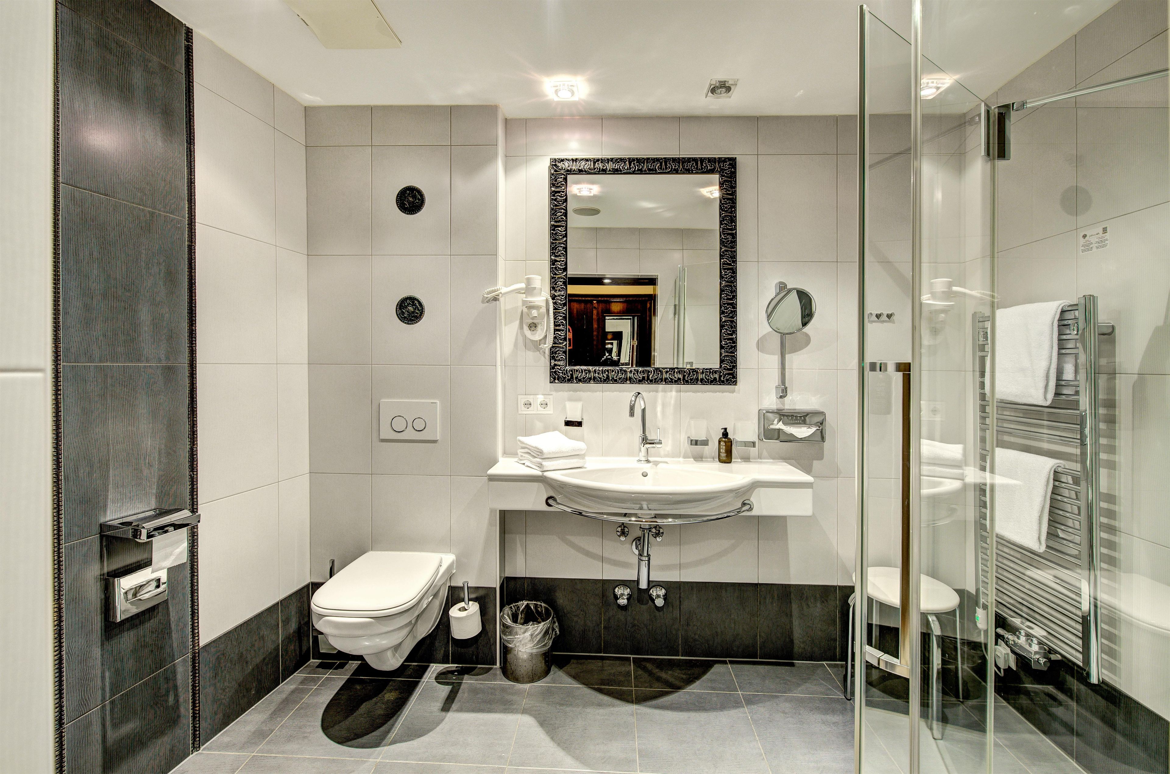 A modern bathroom with a glass shower enclosure, a white sink, and a toilet.