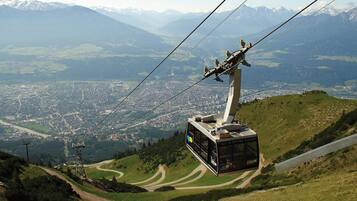 A cable car system with a modern design, a clear view of a town below, and a mountainous landscape in the background.