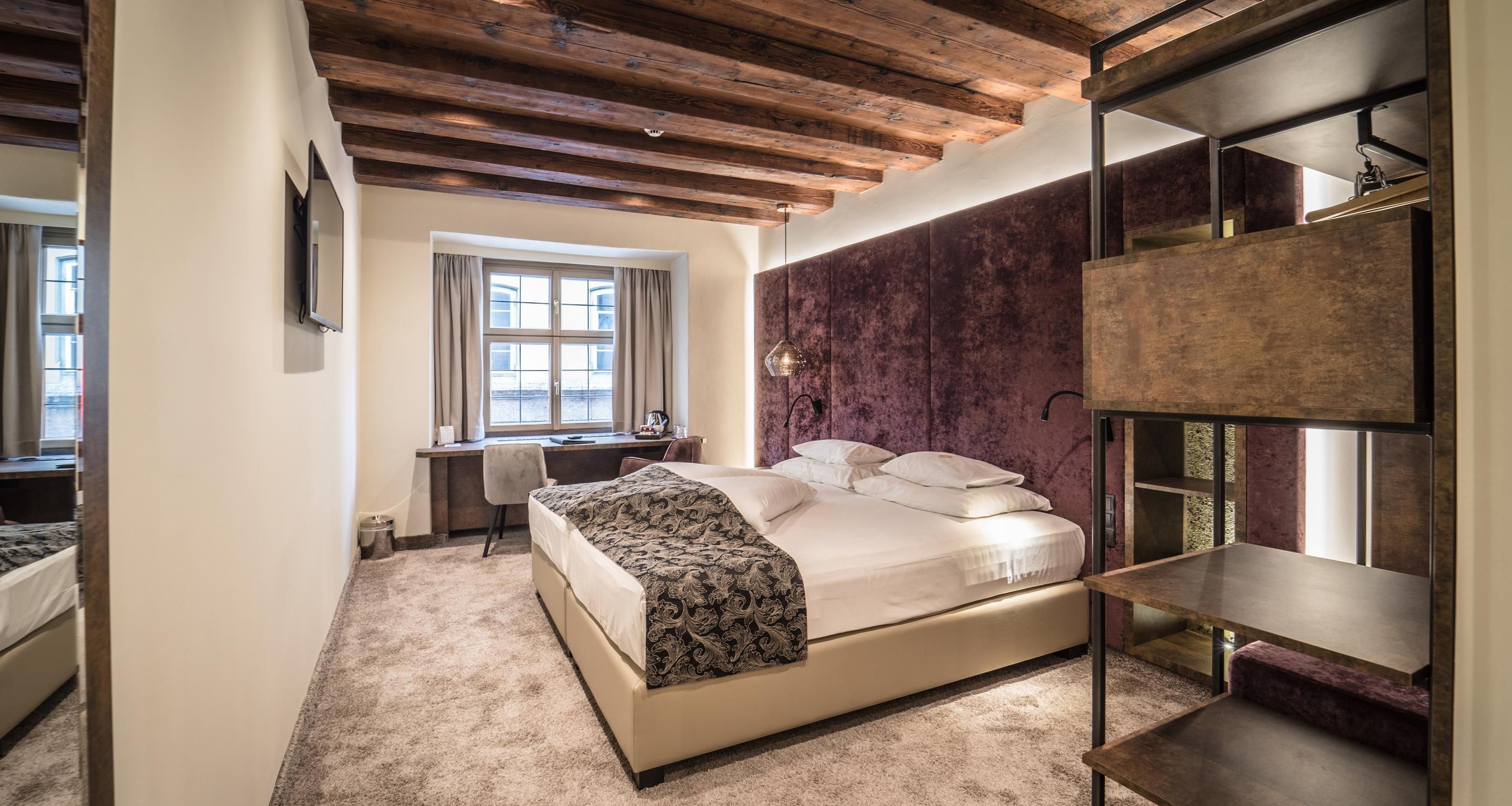 Un dormitorio con cama, escritorio y ventana.
