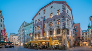 A historic building with ornate architecture, outdoor seating, and a cobblestone street.