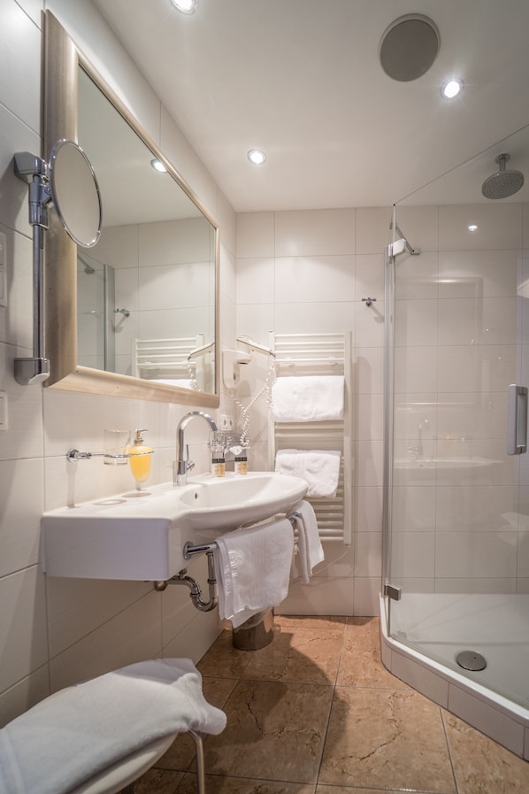 Un baño moderno con lavamanos, espejo y ducha.