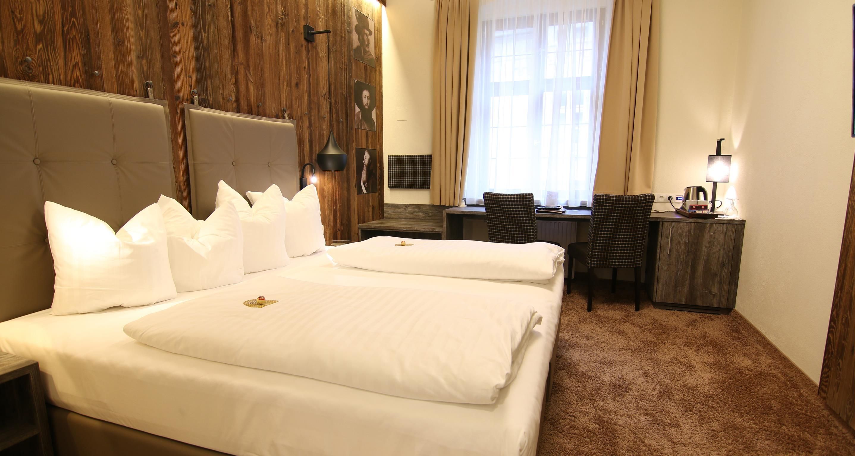 A hotel room with a large bed, a desk, and a chair.